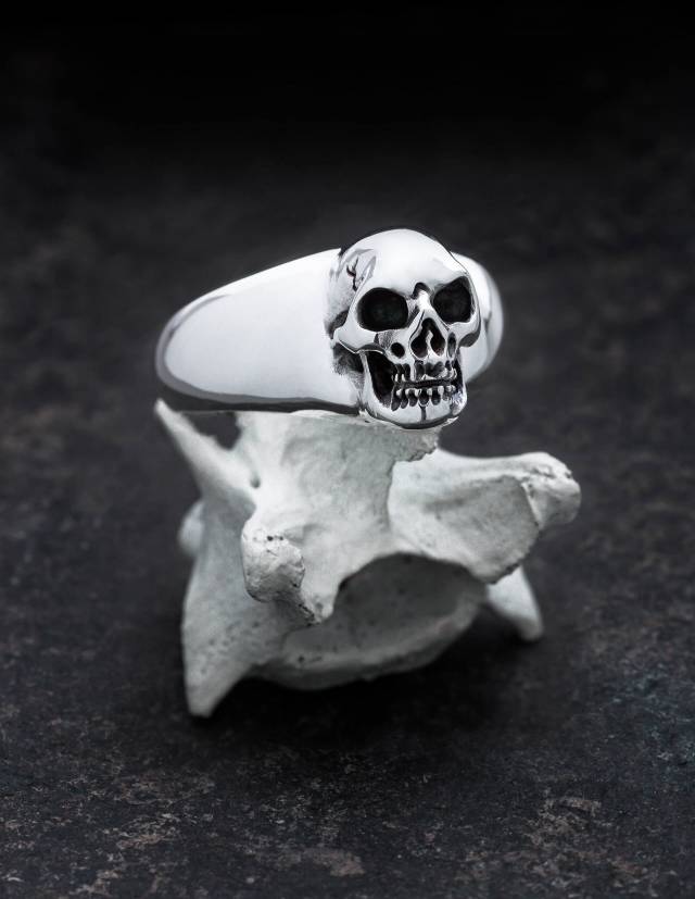 BEHEMOTH: Glatter Siegelring mit Totenkopf für Männer. Plastisch gearbeitet. Alle Vertiefungen sind von Hand geschwärzt. Der Ring liegt im Bild auf einem Knochen.