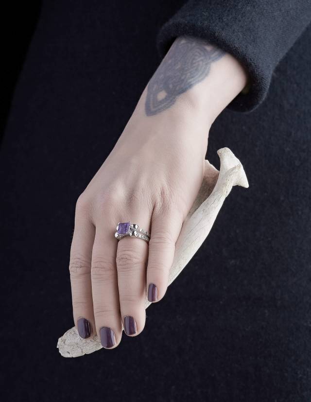 Lethe ist ein massiver Totenkopf Damenring mit schwarzen Diamanten und einem eckigen Amethyst Edelstein aus der Goldschmiede Kipkalinka. Gezeigt an einer Hand.