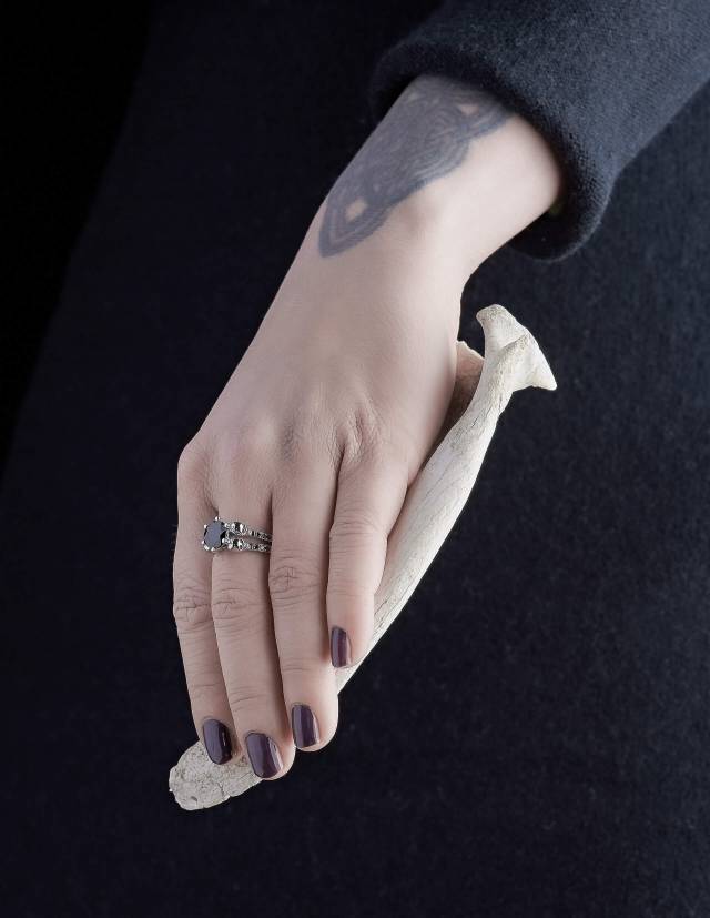 Lilith ist ein eleganter Totenkopfring mit schwarzen Diamanten und einem runden, schwarzen Edelstein. Der Ring ist aus Silber und der perfekte gothic Verlobungsring. Gezeigt an einer Hand.