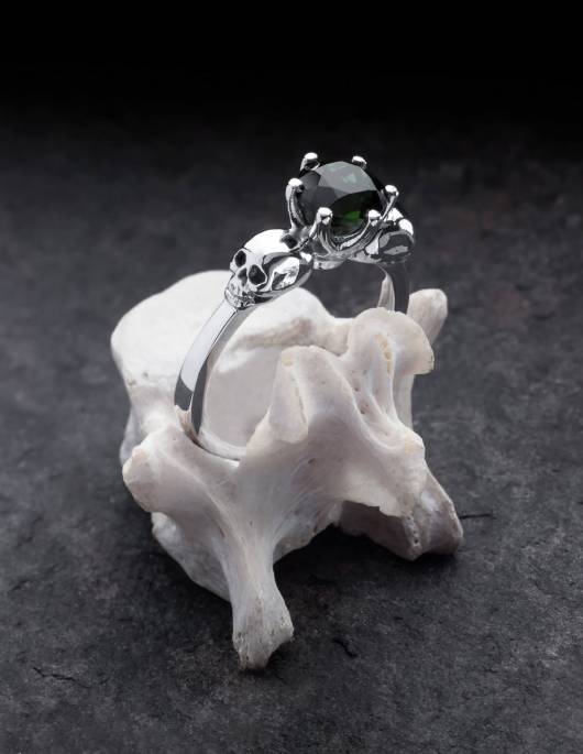 Wandika es un delicado anillo de calavera de plata para señoras. Lleva una pequeña gema negra en un delicado engaste. Se muestra en un hueso.