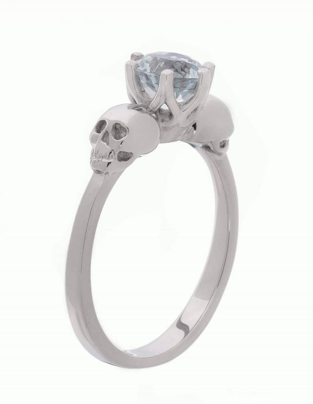 WANDIKA es un delicado anillo de oro blanco con calaveras. Lleva una gema de aguamarina azul claro en su centro. Vista lateral.