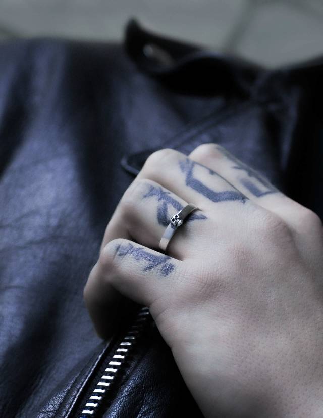Tiny skull ring named sokar worn on a tattooed hand