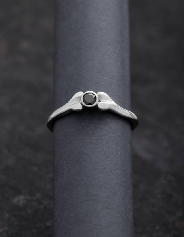 A platinum ring in the shape of a bone with black diamond