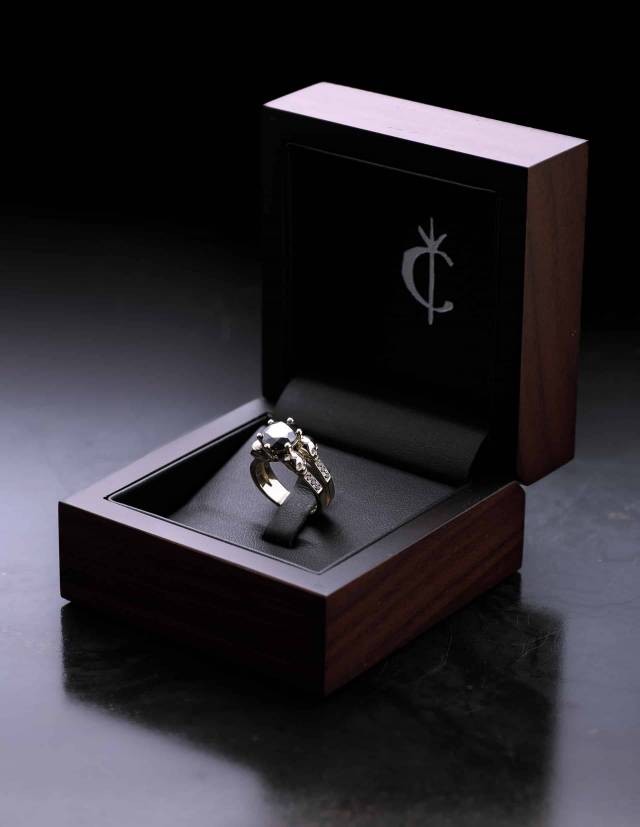 A wooden jewelry box with a golden ring in it on dark background