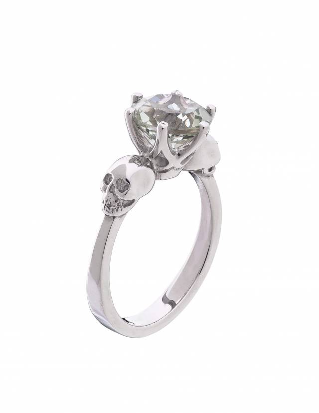 A Small skull ring with light green amethyst made of silver.