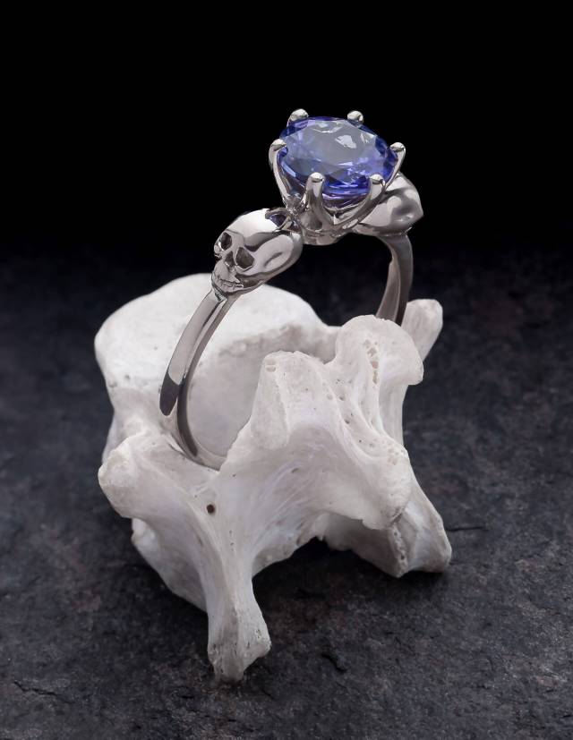 Une petite bague tête de mort en or blanc avec une tanzanite de 2ct posée sur un os.