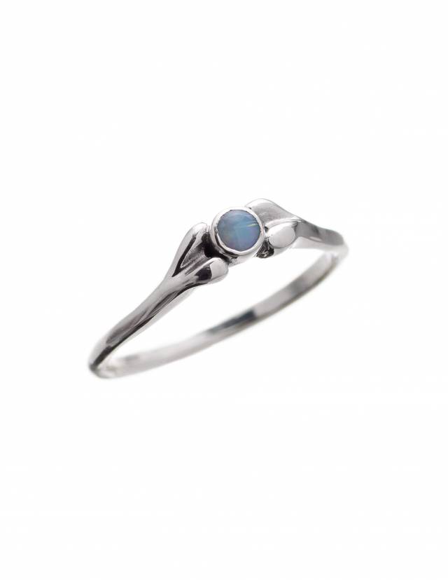 A small ring in the shape of a bone, between the ends sits a round opal gemstone.