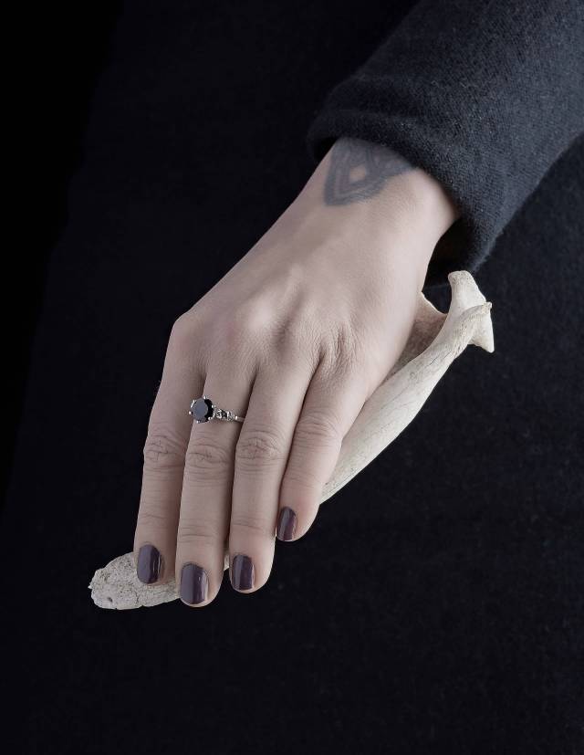 The silver skull ring Wanda worn on a hand which holds a bone.