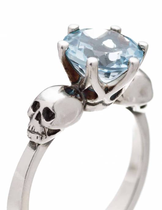 Pastel goth two skull ring with light blue topaz gemstone.