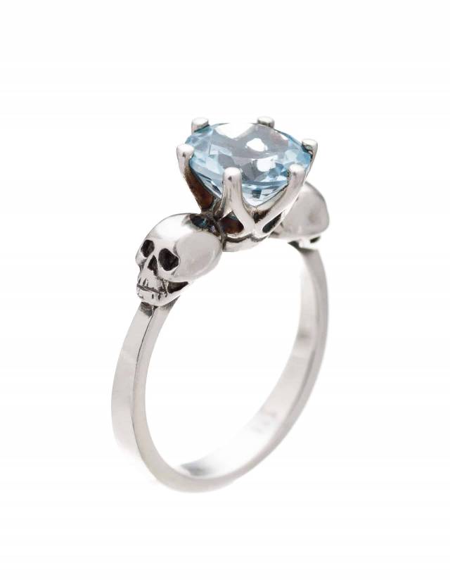 Pastel goth two skull ring with light blue topaz gemstone.