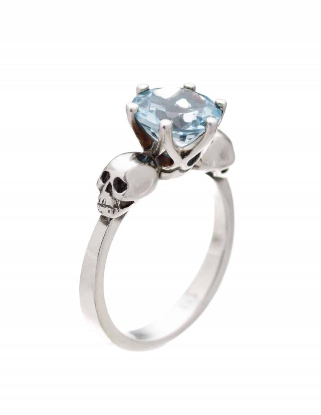 Anillo gótico de dos calaveras con gema de topacio azul claro.