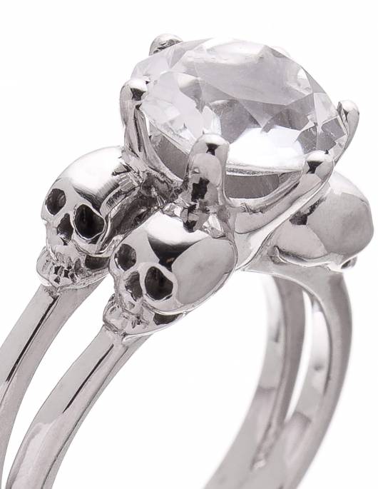 A silver skull ring with a clear rock crystal gemstone.
