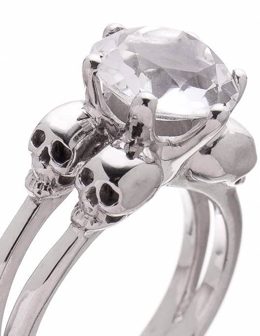 Anillo de calavera de plata con una gema de cristal de roca transparente.