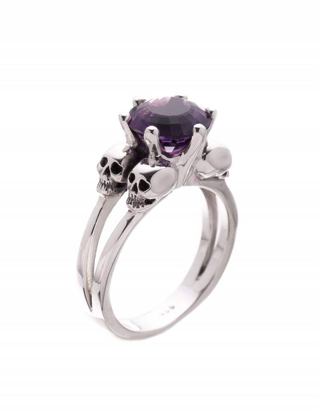 A womens skull ring with 4 little skulls and a purple amethyst gemstone.