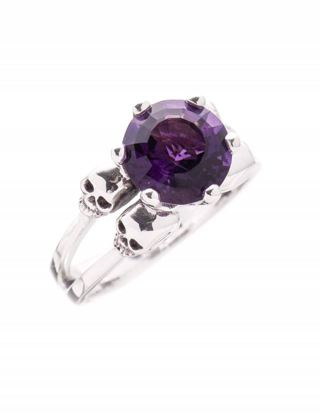A skull ring named Varla made of sterling sliver with a purple gemstone.