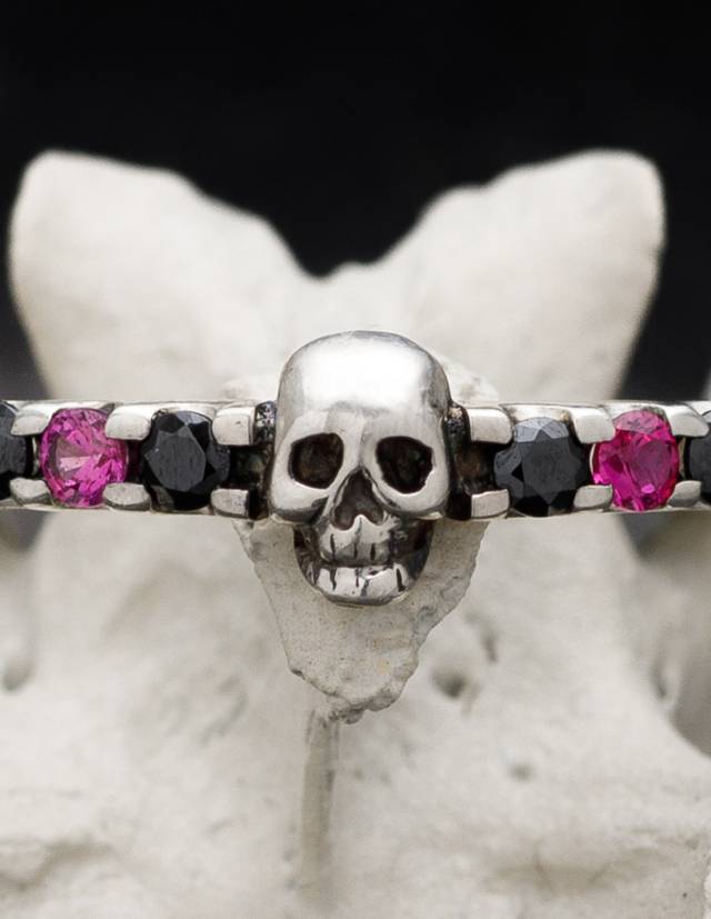Detail of dainty skull wedding ring SALACIA with pink and black gemstones.