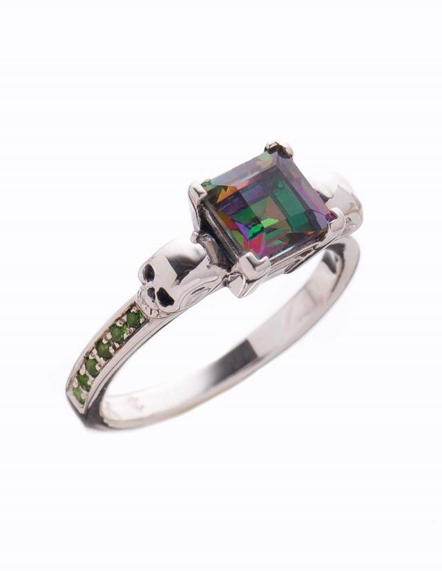 A dainty skull engagement ring with a princess cut mystic topaz gemstone and small stones in the bands by Kipkalinka.