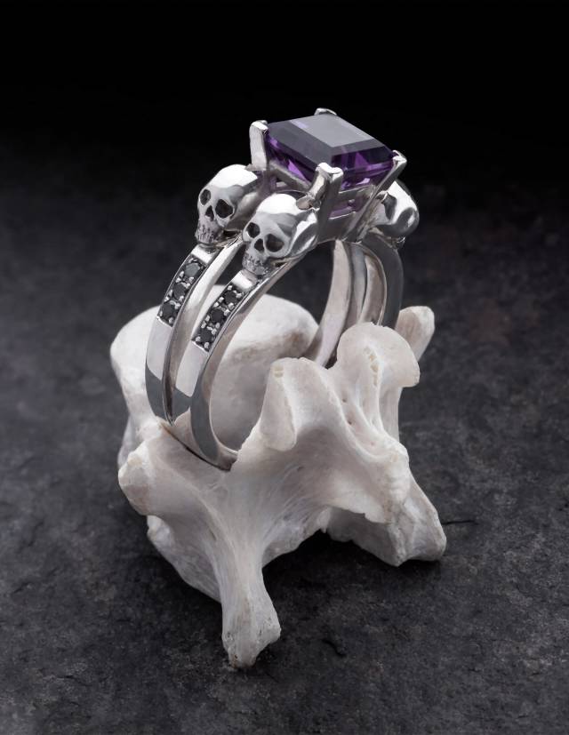 Elegant goth ring with 4 skulls and princess cut purpla amethyst gemstone, adorned with black diamonds.