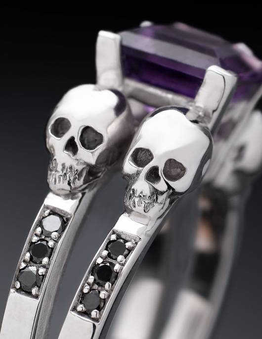 Detailed skull ring for women with princess cut gemstone and black diamonds, close up.