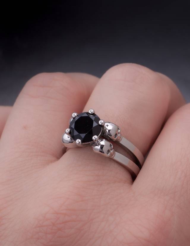 A gothic engagement ring made of silver with a round black gemstone worn, close up.