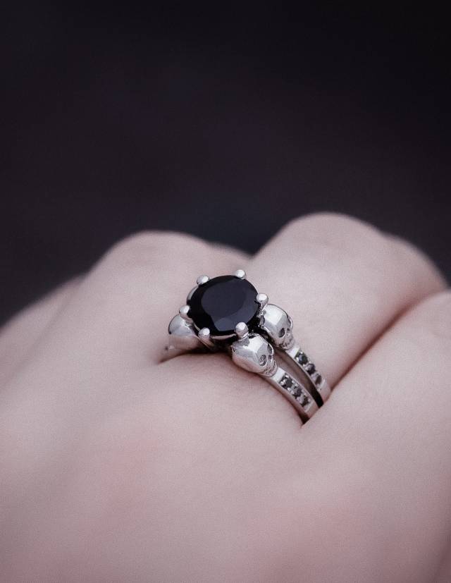 A gothic engagement ring made of silver with black gemstones worn.