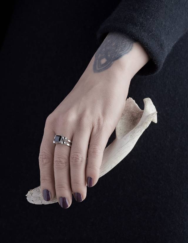 Black goth ring made of sterling silver shown on a hand holding a bone.