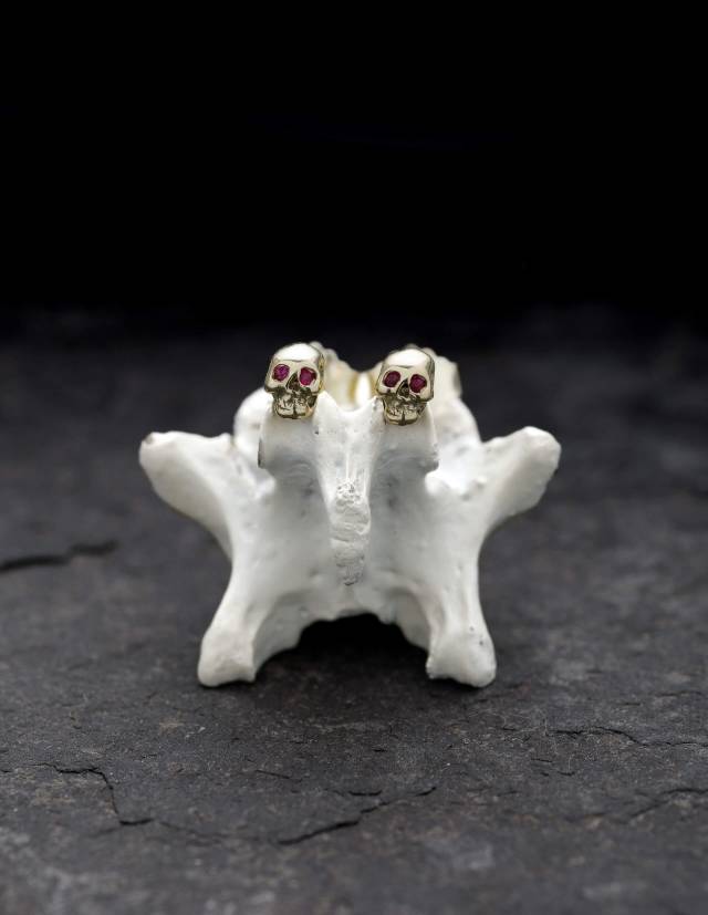 Memento mori skull post earrings in yellow gold with ruby eyes.