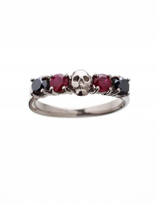 A detailed skull ring made of solid white gold with rubys and natural black diamonds.